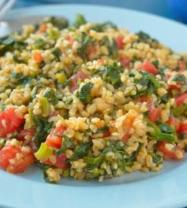 Bulgur mit Spinat und Tomate auf einem hellblauen Teller