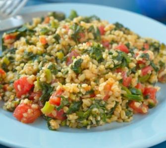 Bulgur mit Spinat und Tomate auf einem hellblauen Teller