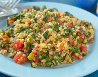 Bulgur mit Spinat und Tomate auf einem hellblauen Teller