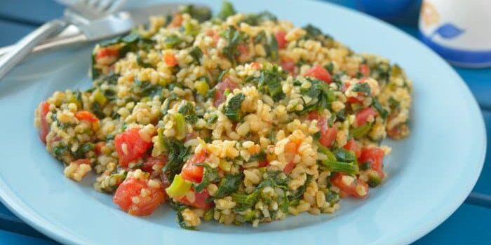 Bulgur mit Spinat und Tomate auf einem hellblauen Teller