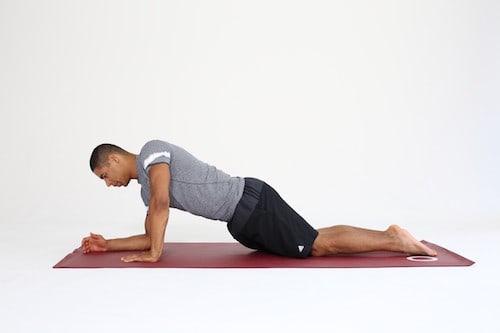 Mann macht Übung Walking Plank auf dunkelroter Trainingsmatte -Plank Varianten