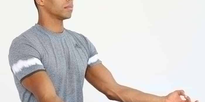 Progressive Muskelrelaxation Mann sitzt im Schneidersitz und macht progressive Muskelrelaxation