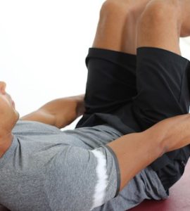 Mann macht Crunches auf dunkelroter Trainingsmatte