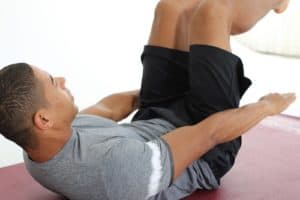 Mann macht Crunches auf dunkelroter Trainingsmatte