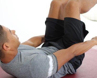 Mann macht Crunches auf dunkelroter Trainingsmatte