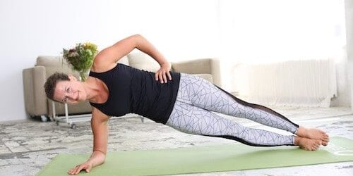 Frau macht Side Plank auf hellgrüner Trainingsmatte