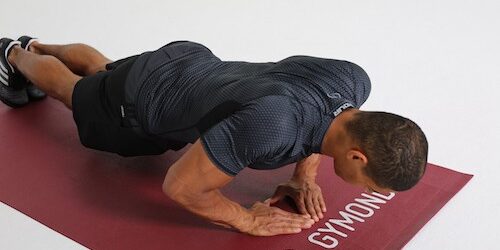 Mann macht Diamond Push Ups auf dunkelroter Trainingsmatte