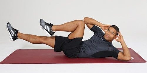 Mann macht Diagonal Crunches auf dunkelroter Trainingsmatte