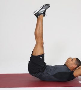 Mann macht Reverse Crunches auf dunkelroter Trainingsmatte