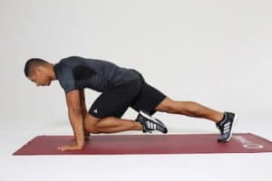 Mann macht Mountain Climbers auf dunkelroter Trainingsmatte