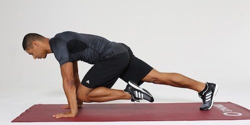 Mountain Climbers Mann macht Mountain Climbers auf dunkelroter Trainingsmatte