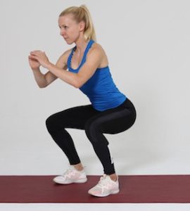 Frau macht Squat auf roter Trainingsmatte