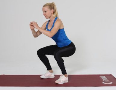 Frau macht Squat auf roter Trainingsmatte