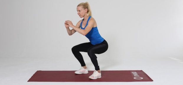 Frau macht Squat auf roter Trainingsmatte