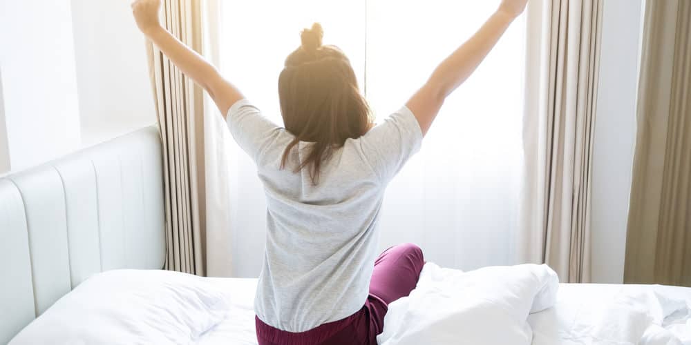 Aufstehen Morgen Routine - Frau räkelt sich im Bett nach dem Aufstehen