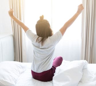 Morgen Routine - Frau räkelt sich im Bett nach dem Aufstehen