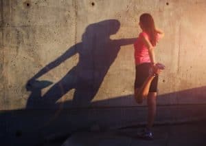 Sportlerin wärmt sich vor dem Training auf vor einer Wand.