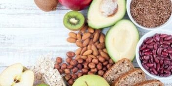 Ein Tisch mit Ballaststoffreichen Lebensmitteln wie Äpfeln, Vollkornprodukte, Bohnen