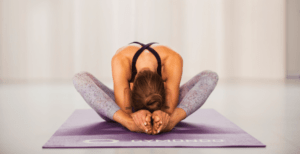 Valerie Junger sitzt im Schneidersitz auf einer lila Trainingsmatte von Gymondo und macht Yin Yoga