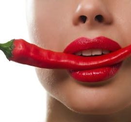 Frau mit Chilischote im Mund mit Lippenstift
