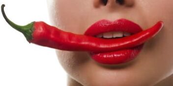 Frau mit Chilischote im Mund mit Lippenstift