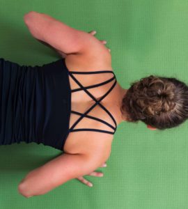 Junge Frau auf einer hellgrünen Trainingsmatte macht Liegestützen
