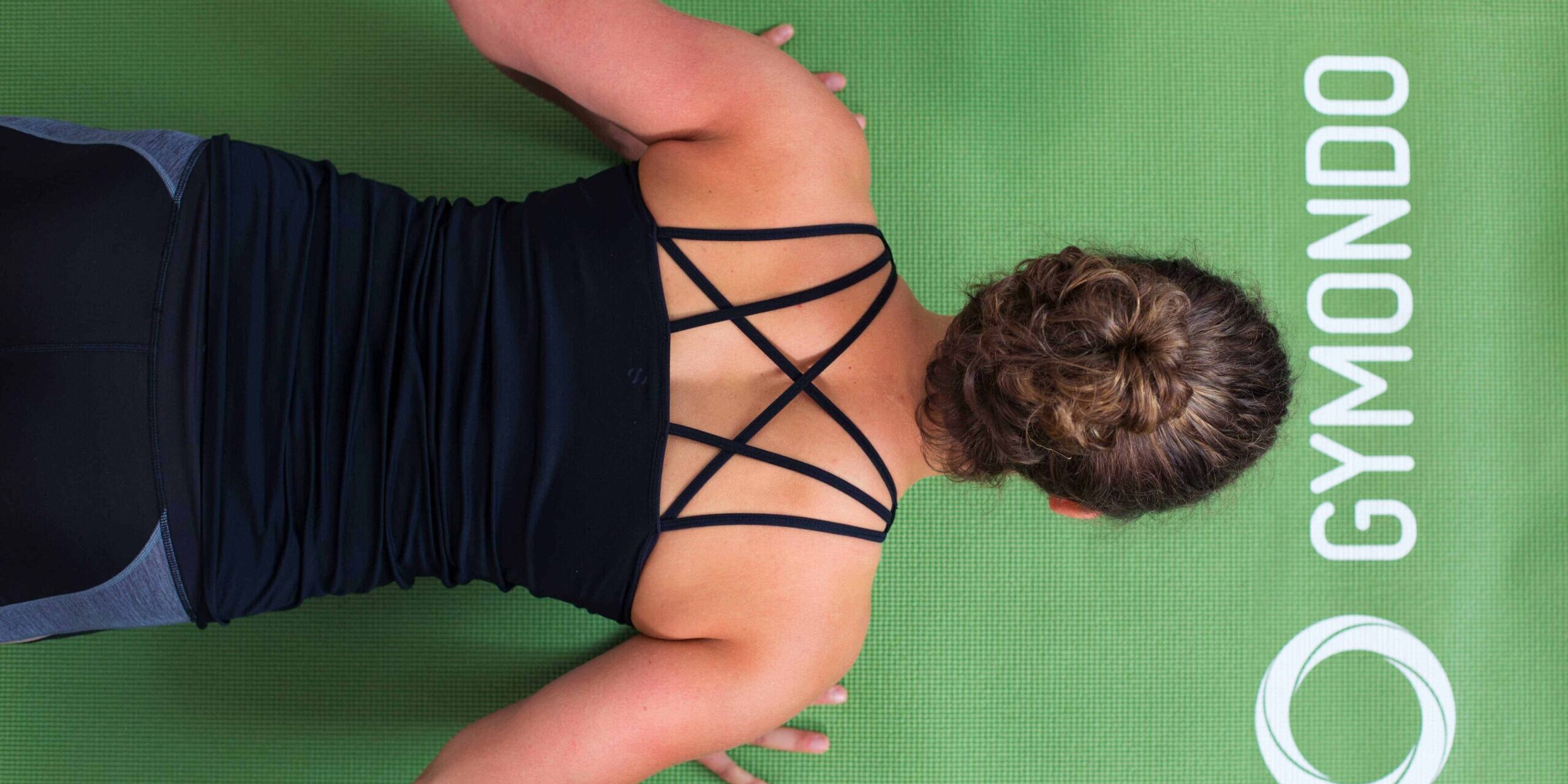 Junge Frau auf einer hellgrünen Trainingsmatte macht Liegestützen