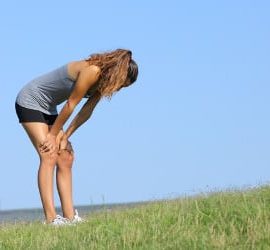 Eine Sportlerin mit Heuschnupfen steht erschöpft auf einer Wiese.