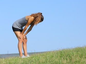 Eine Sportlerin mit Heuschnupfen steht erschöpft auf einer Wiese.