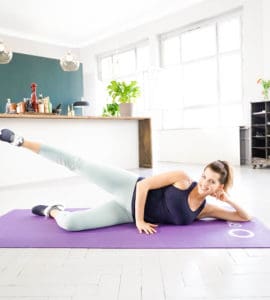 Sarah Harrison liegt auf einer Trainingsmatte und macht eine Übung aus GET IN SHAPE by Team Harrison