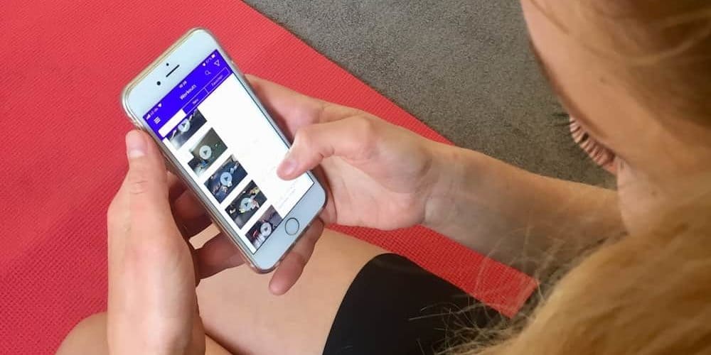 Gymondo Erfahrung – Online Fitness im Praxis Test Junge Frau auf roter Trainingsmatte testet Gymondo App