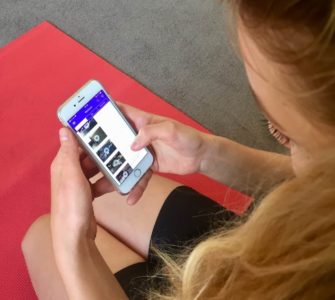 Junge Frau auf roter Trainingsmatte testet Gymondo App