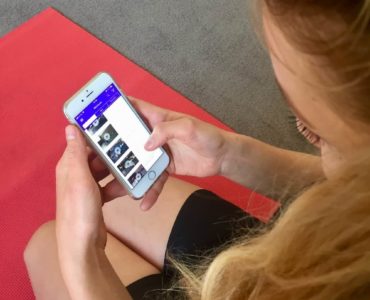 Junge Frau auf roter Trainingsmatte testet Gymondo App