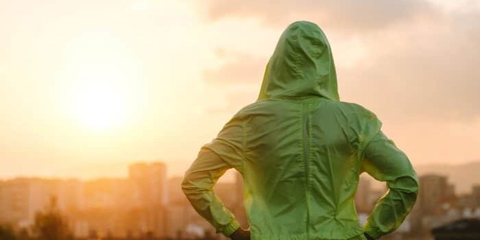 Motivation Sonnenuntergang grüner Hoodie Frau mit grünem Kapuzenpulli schaut in den Sonnenuntergang.
