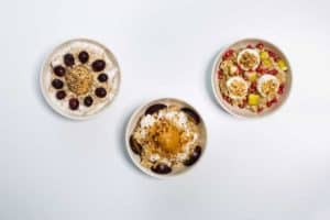 3 weiße Schalen mit Haferbrei garniert mit Früchten und Nüssen, Oat Meal Bowls
