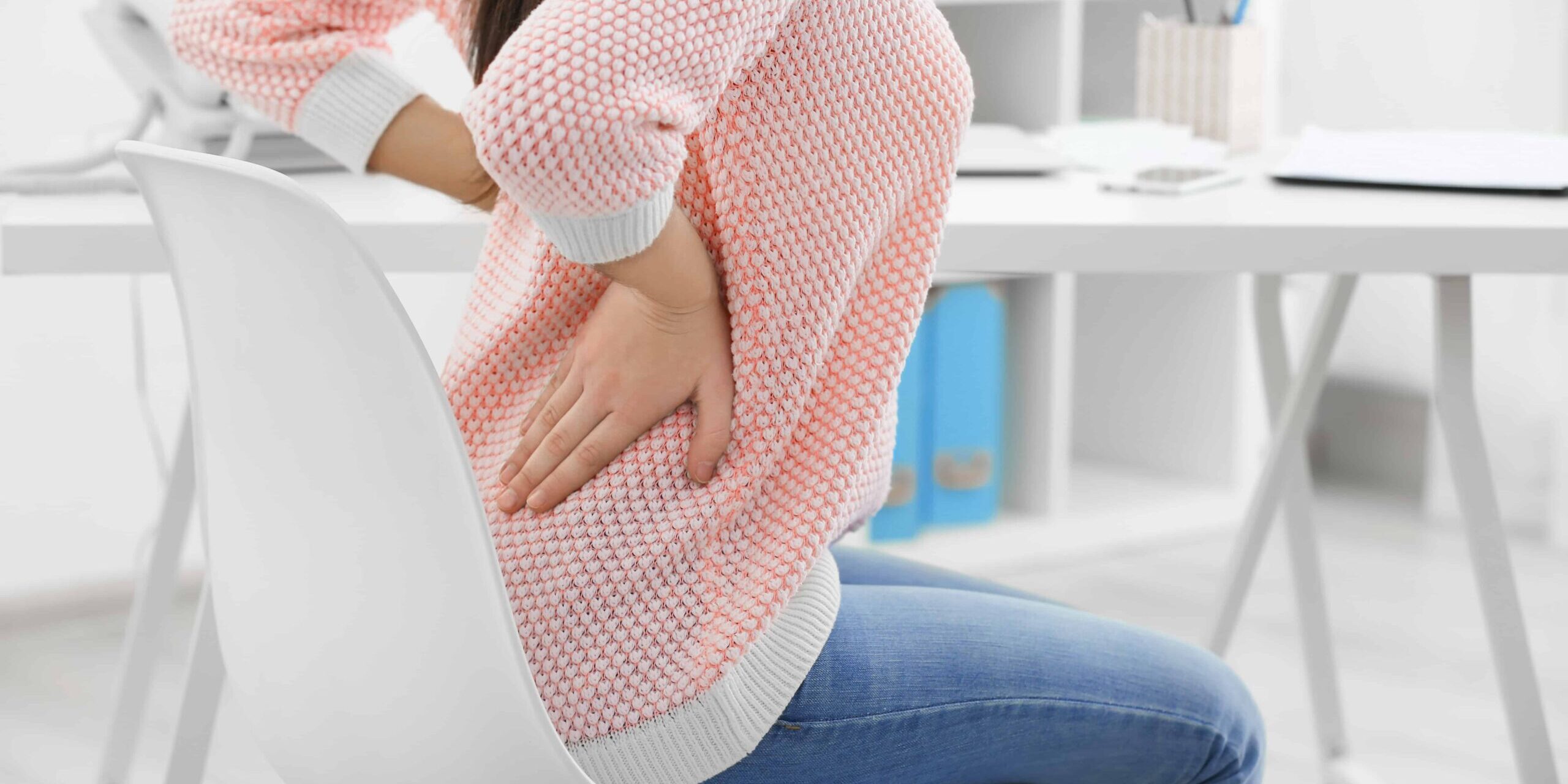 Frau stützt die Hände im Rücken ab, hat Schmerzen Rücken