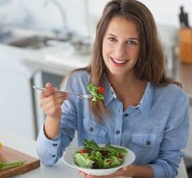 Eine Frau in der Küche beim Essen eines Salats