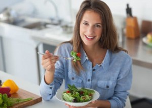 Eine Frau in der Küche beim Essen eines Salats