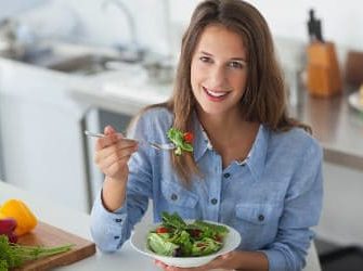 Eine Frau in der Küche beim Essen eines Salats