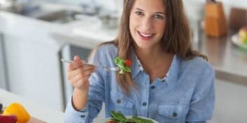 Eine Frau in der Küche beim Essen eines Salats