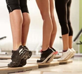 Drei Frauen, die auf einer Holzleiste Calf Raises ausführen