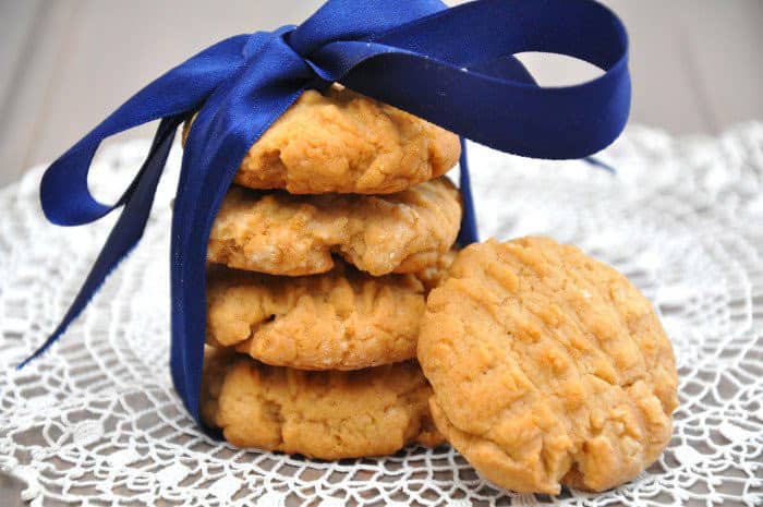 Vier aufeinandergestapelte Erdnussbuttercookies, zusammengehalten durch eine große blaue, seidene Schleife