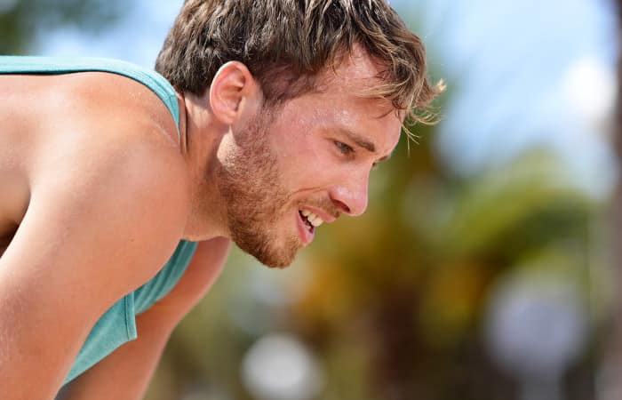 Mann stemmt nach anstrengender Fitness-Einheit die Arme auf die Knie