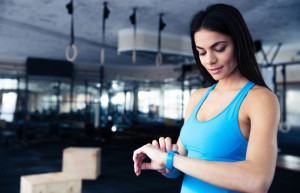 Frau im blauen Shirt schaut auf ihr Fitness Armband