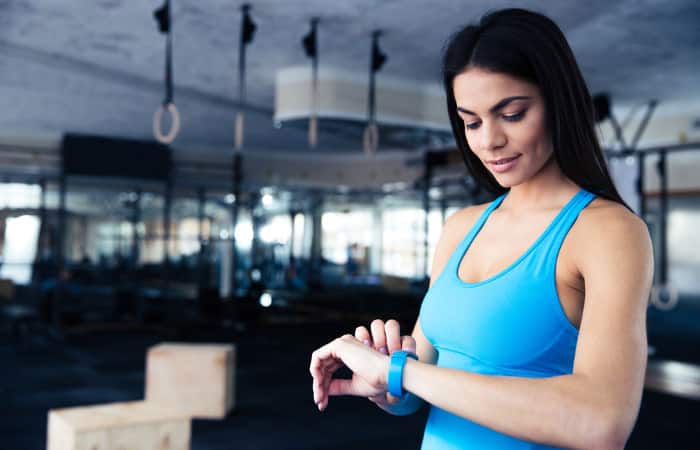 Frau im blauen Shirt schaut auf ihr Fitness Armband