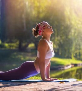 Frau führt unter freiem Himmel die Yogaübung Cobra aus