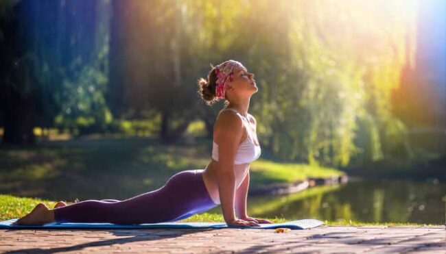 frau-cobrauebung Frau führt unter freiem Himmel die Yogaübung Cobra aus