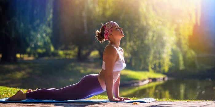 Frau führt unter freiem Himmel die Yogaübung Cobra aus