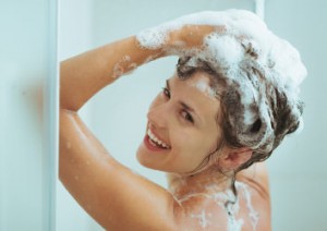 Duschende Frau beim Einshampoonieren ihrer Haare