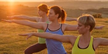 Sportlerinnen machen die Gleichgewichtsübung "Krieger 3"